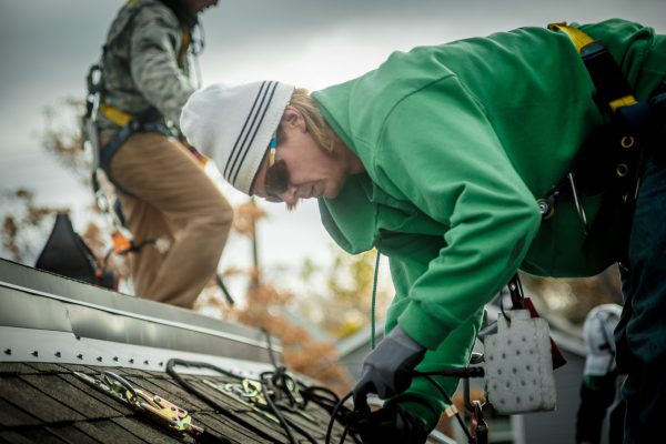 Construction crew installing solar panels on a house